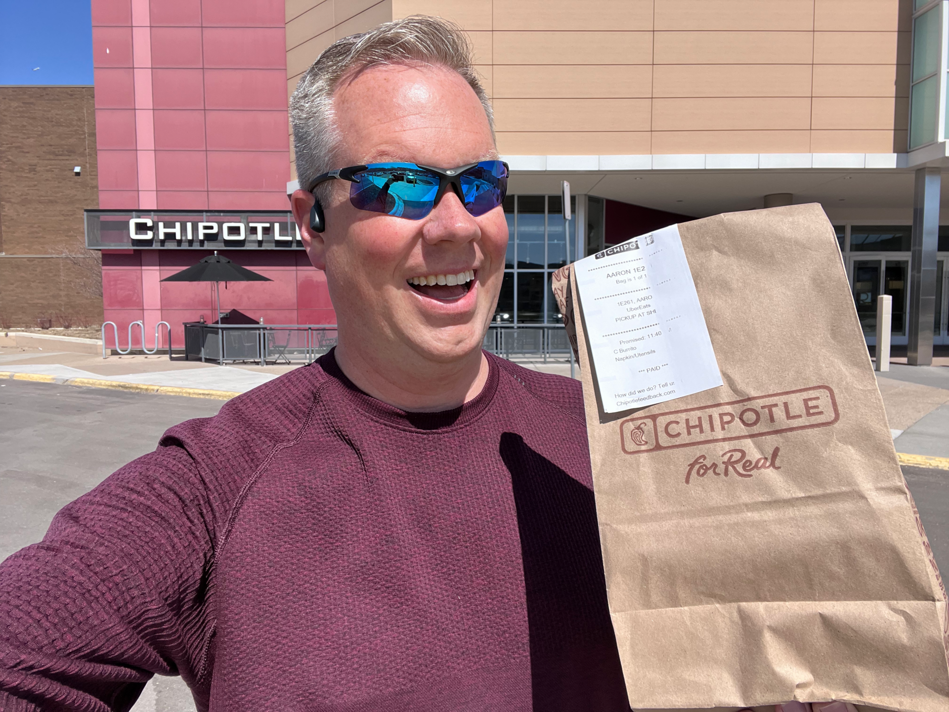 Aaron Hurd holding a Chipotle bag in front of a Chipotle.