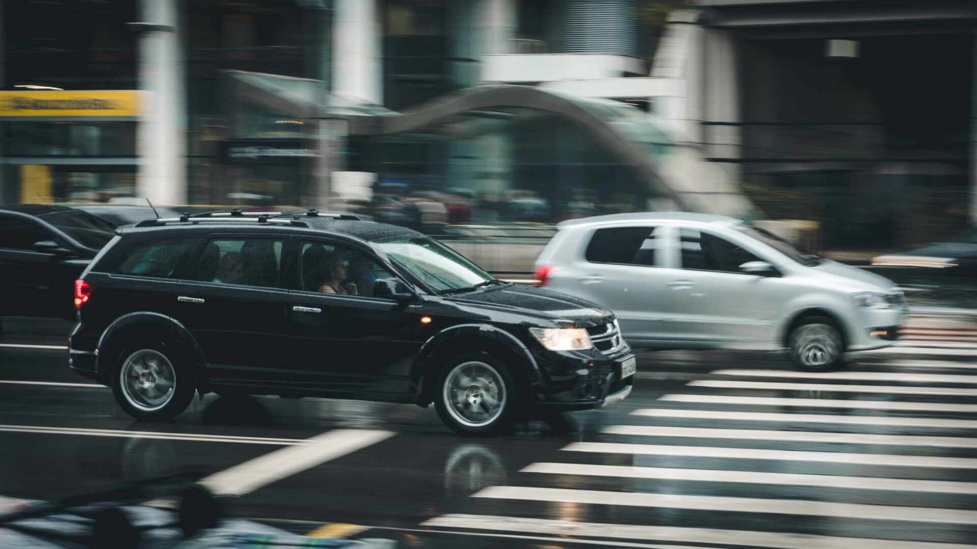 Black suv beside grey auv crossing the pedestrian line during daytime